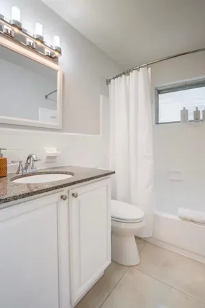 a bathroom with a granite countertop sink a toilet and a mirror