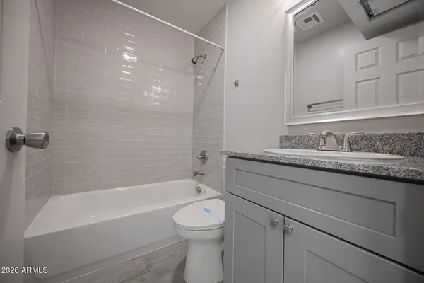 a bathroom with a granite countertop sink a toilet and bathtub