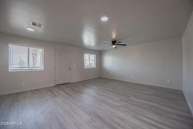 an empty room with wooden floor and windows
