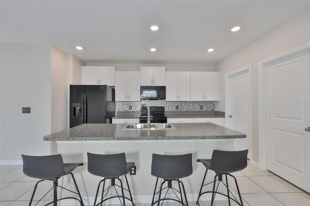 797 Olive Conch Street Ruskin, FL 33570 - Photo 11 of 53 a kitchen with stainless steel appliances granite countertop a stove a sink a refrigerator and a dining table with wooden cabinet