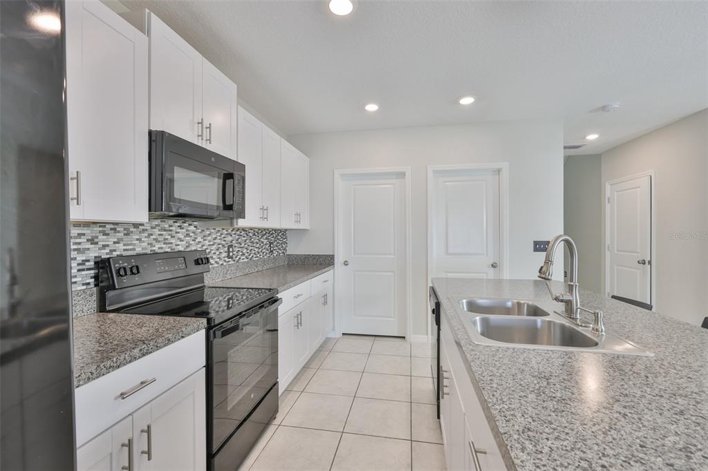 797 Olive Conch Street Ruskin, FL 33570 - Photo 12 of 53 a kitchen with granite countertop a sink a stove and cabinets