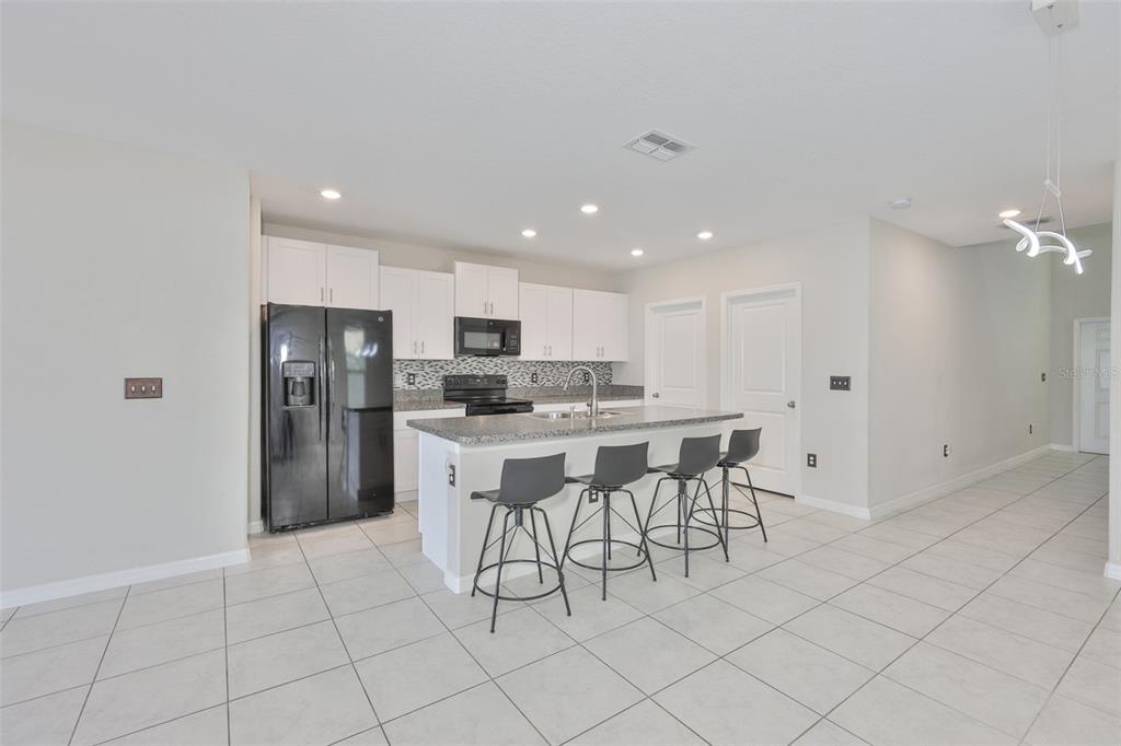 797 Olive Conch Street Ruskin, FL 33570 - Photo 13 of 53 a kitchen with stainless steel appliances kitchen island granite countertop a refrigerator a stove a sink and white cabinets with a dining table