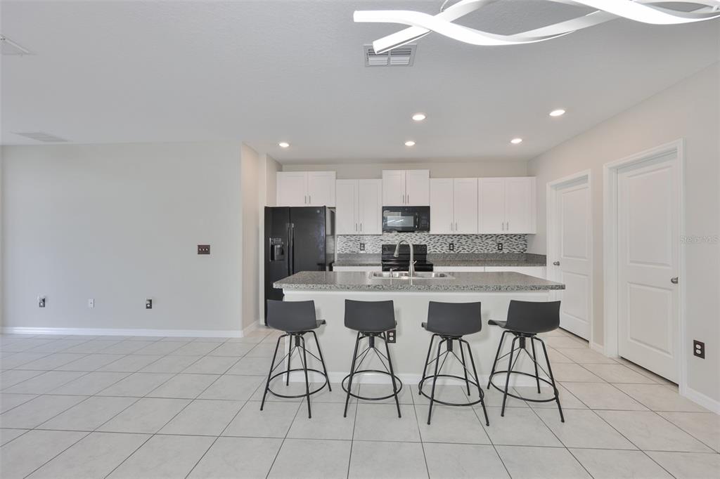 797 Olive Conch Street Ruskin, FL 33570 - Photo 9 of 53 a kitchen with stainless steel appliances kitchen island granite countertop a sink a stove a refrigerator and white cabinets with wooden floor