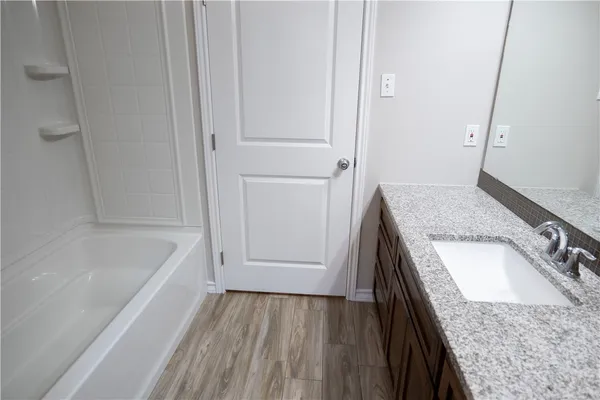 a bathroom with a granite countertop sink and mirror with bathtub