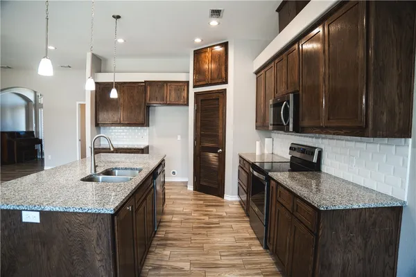 a kitchen with stainless steel appliances granite countertop a sink stove and refrigerator