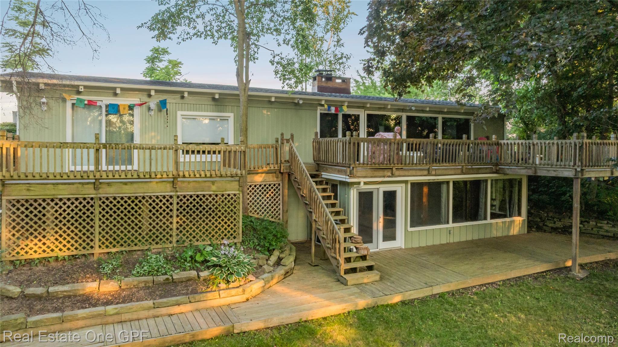 5068 Atkins Road North Street, MI 48049 - Photo 72 of 78 Two-story residence featuring light green siding, multiple wood-finish decks, and a stone-edged garden bed