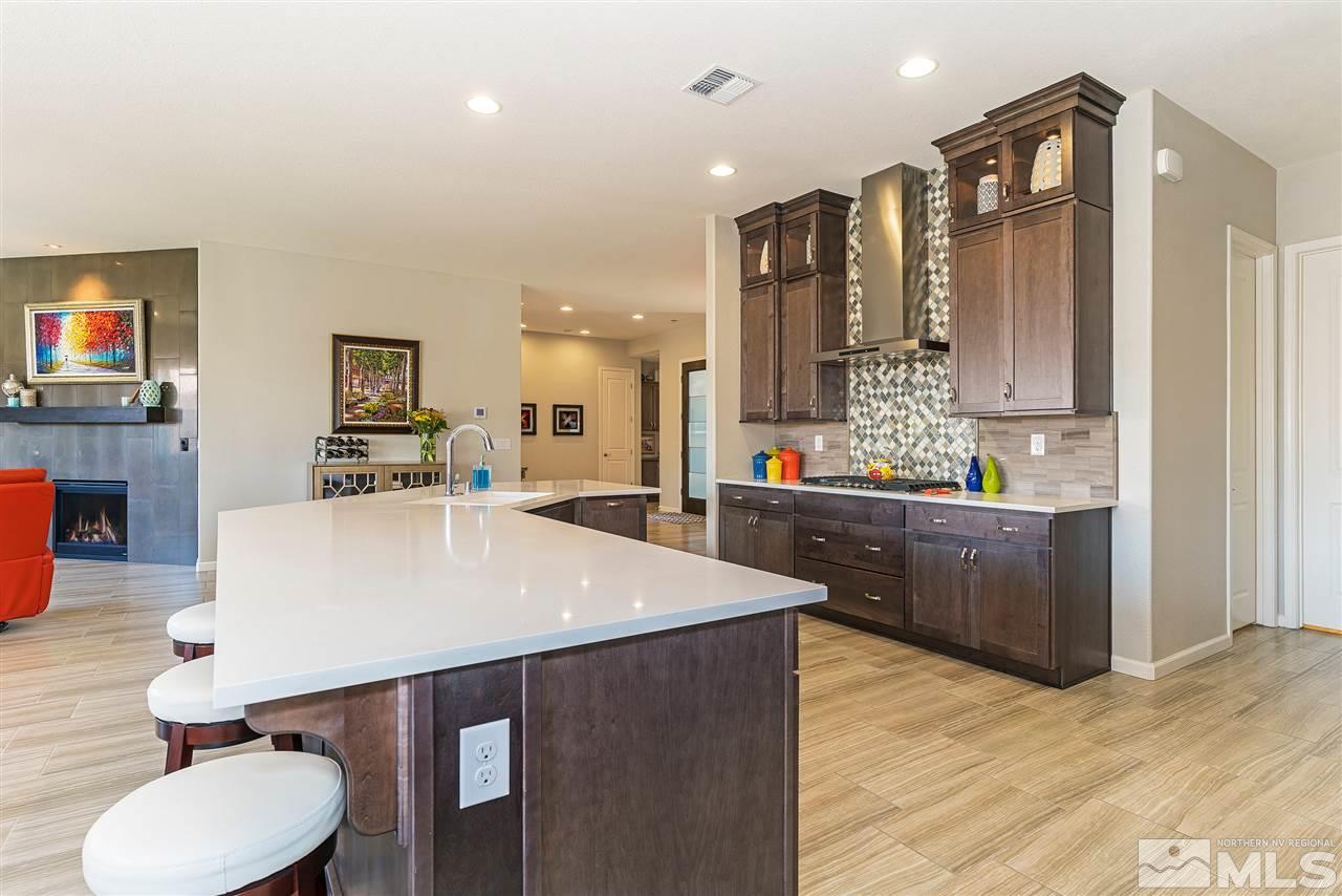 9818 Dyevera Lane Reno, NV 89521 - Photo 8 of 25 a large kitchen with stainless steel appliances kitchen island granite countertop a table chairs sink and cabinets