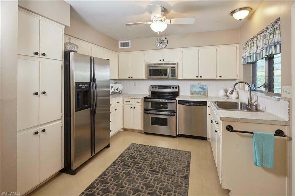 1829 Mandarin Road Naples, FL 34102 - Photo 4 of 14 a kitchen with stainless steel appliances a refrigerator sink and white cabinets