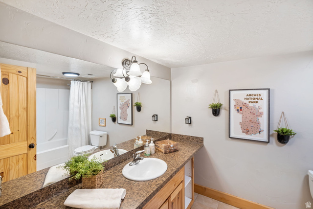 2013 North River View Road Huntsville, UT 84317 - Photo 31 of 53 Bathroom featuring vanity, a textured ceiling, shower / bath combo with shower curtain, and light tile patterned floors
