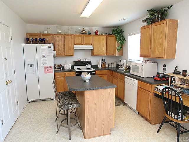 4102 Springfield Creek Drive Raleigh, NC 27616 - Photo 5 of 10 a kitchen with stainless steel appliances granite countertop a table chairs sink refrigerator and cabinets
