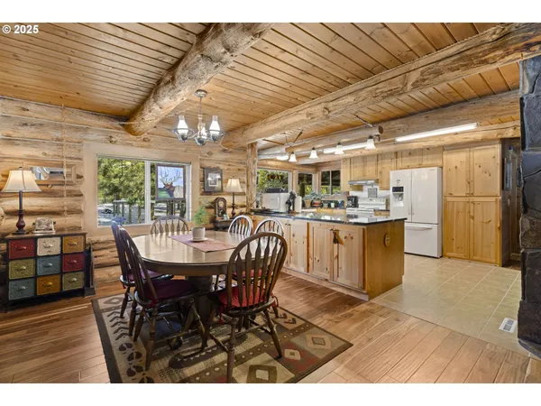 a dining hall with stainless steel appliances granite countertop a table chairs and a wooden floor