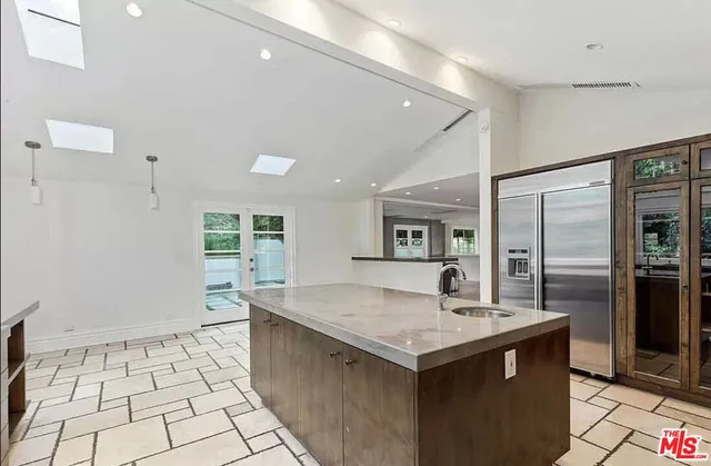 a kitchen with granite countertop a sink and refrigerator