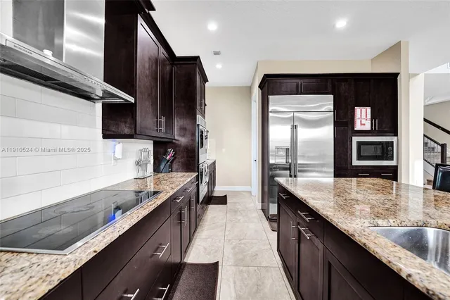 a kitchen with stainless steel appliances granite countertop a sink a stove and a refrigerator
