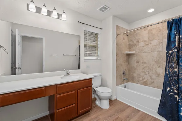 a bathroom with a granite countertop sink a toilet a mirror a bathtub and shower