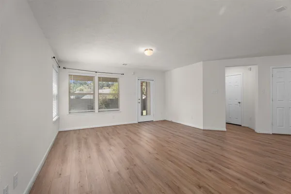 an empty room with wooden floor and windows