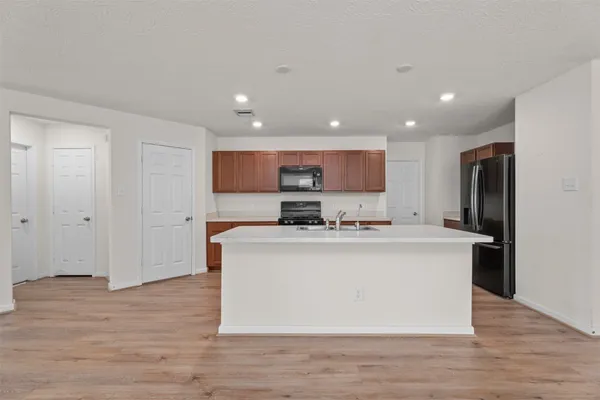 a view of kitchen with stainless steel appliances granite countertop refrigerator stove top oven and cabinets