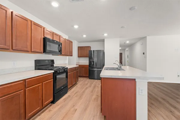 a kitchen with stainless steel appliances granite countertop a stove top oven a sink and a refrigerator