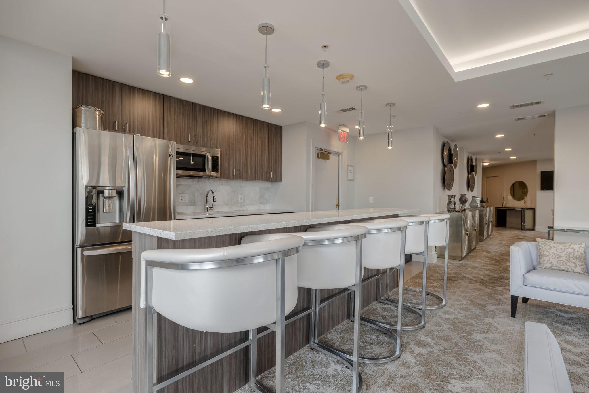 3600 South Glebe Road, Unit 409W Arlington, VA 22202 - Photo 22 of 34 a kitchen with stainless steel appliances kitchen island granite countertop a table chairs refrigerator and microwave