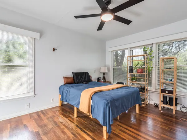 a bedroom with a bed and a large window with wooden floor