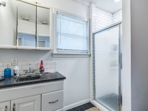 a kitchen with stainless steel appliances granite countertop white cabinets and a potted plant