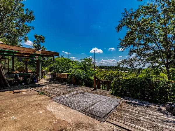 a view of a patio with table and chairs under an umbrella with potted plants