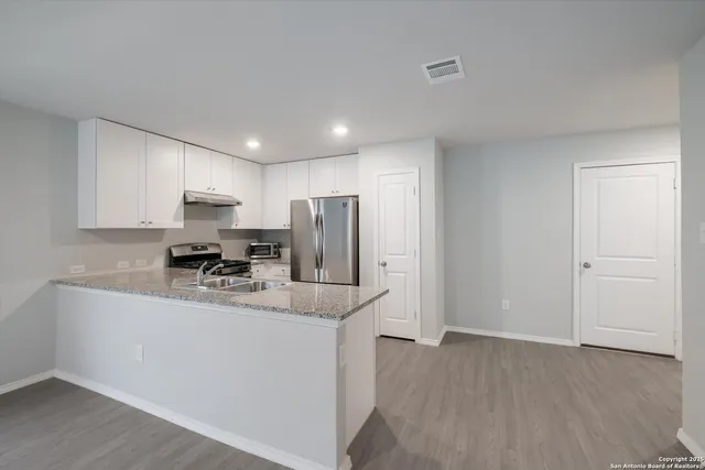 a kitchen with stainless steel appliances granite countertop a sink a refrigerator and a granite counter tops