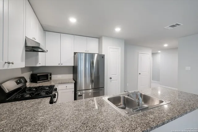 a kitchen with kitchen island granite countertop a sink stove and refrigerator