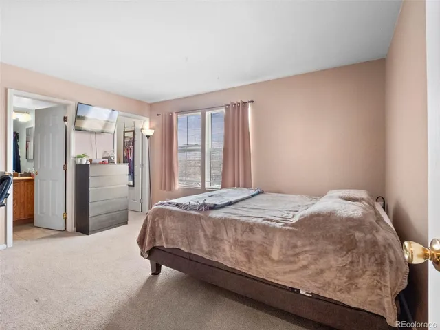 a bed sitting in a spacious bedroom next to a window