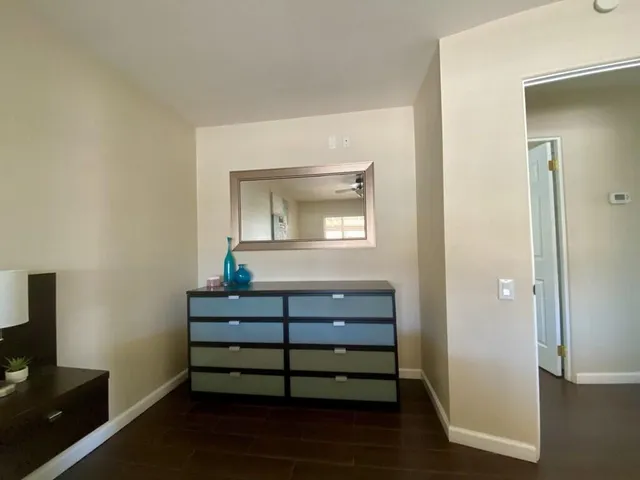 a room with a mirror on dresser and a wooden floor