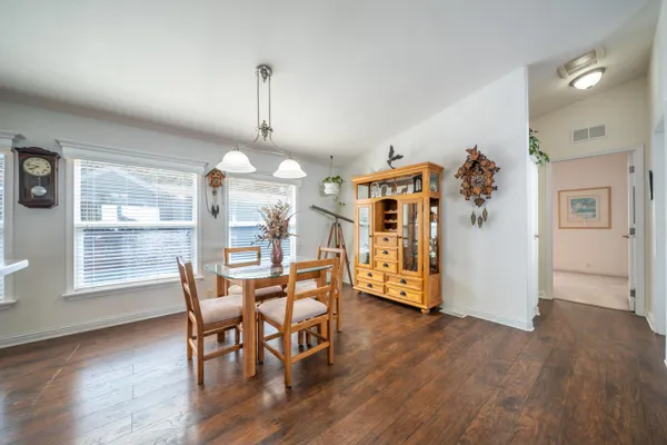 a kitchen with stainless steel appliances granite countertop a refrigerator a stove a sink and white cabinets with wooden floor