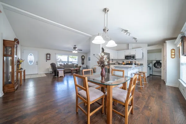 a kitchen with stainless steel appliances granite countertop white cabinets a sink a stove a refrigerator and island with wooden floor