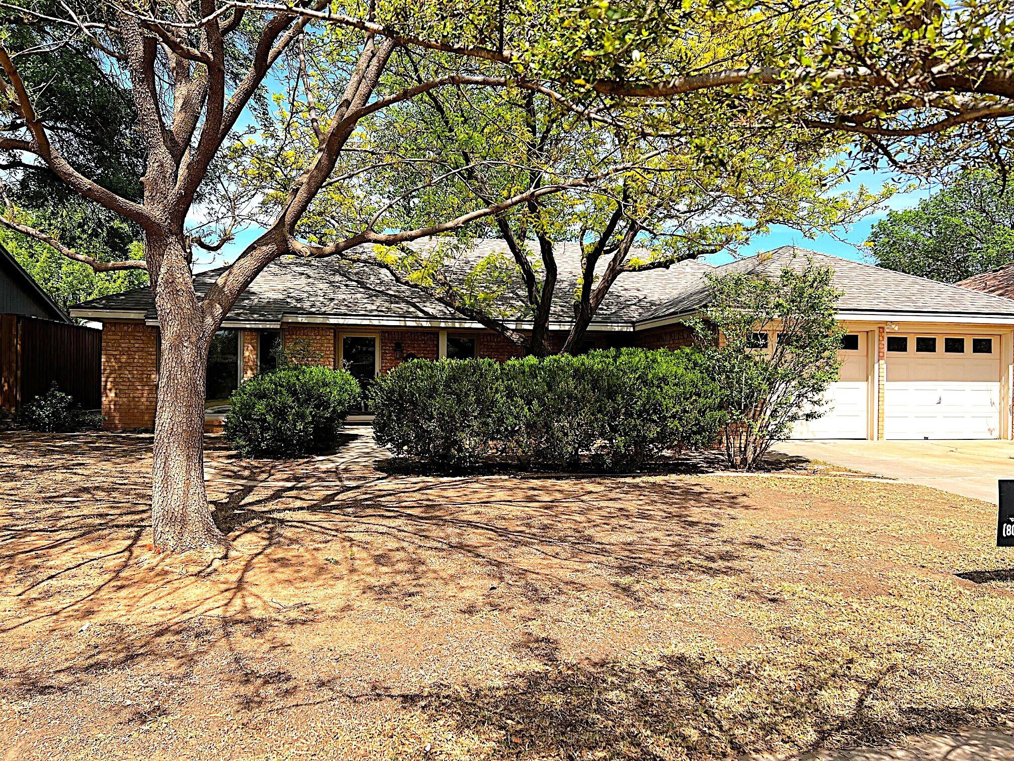 a view of yellow house with large trees