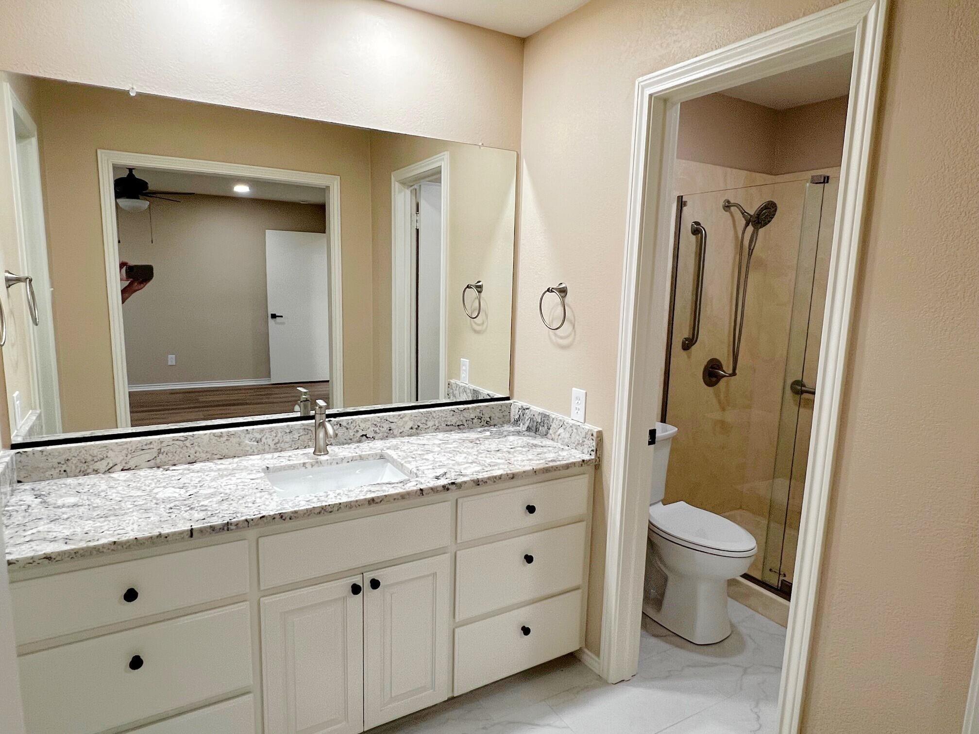 3506 86th Street Lubbock, TX 79423 - Photo 14 of 29 a bathroom with a granite countertop sink a toilet and a mirror