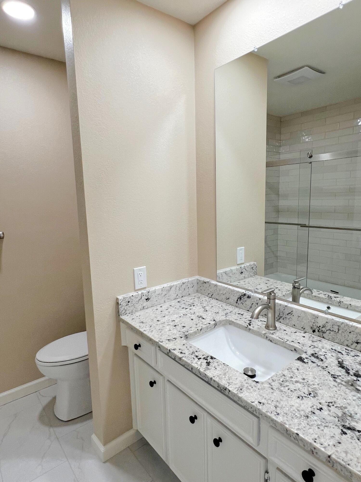3506 86th Street Lubbock, TX 79423 - Photo 18 of 29 a bathroom with a granite countertop sink a toilet and a mirror