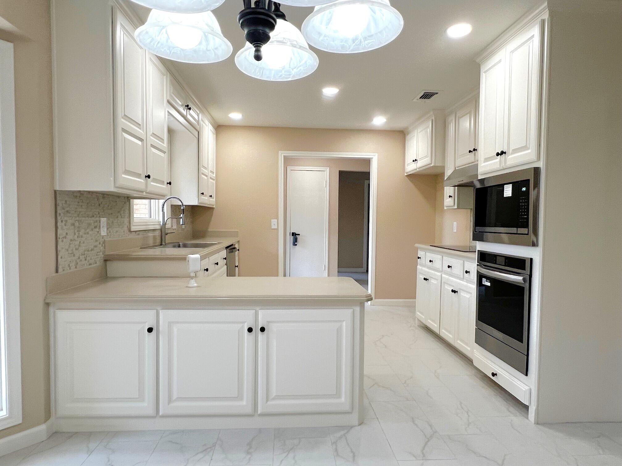 3506 86th Street Lubbock, TX 79423 - Photo 5 of 29 a kitchen with white cabinets and stainless steel appliances
