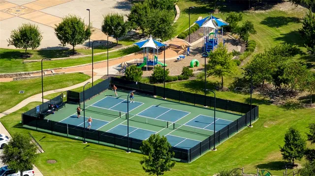 a view of a tennis ground with large trees
