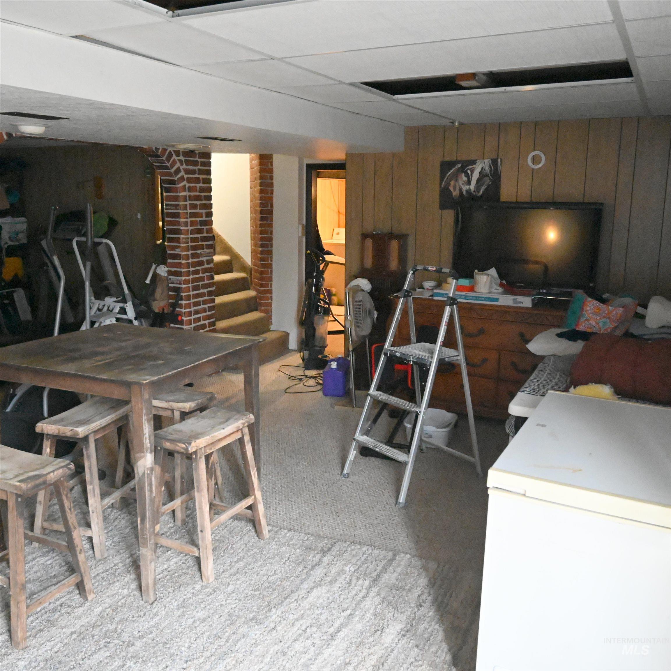 646 Riverside Avenue Orofino, ID 83544 - Photo 17 of 23 Finished basement with wood walls, white refrigerator, stairway, light carpet, and a paneled ceiling