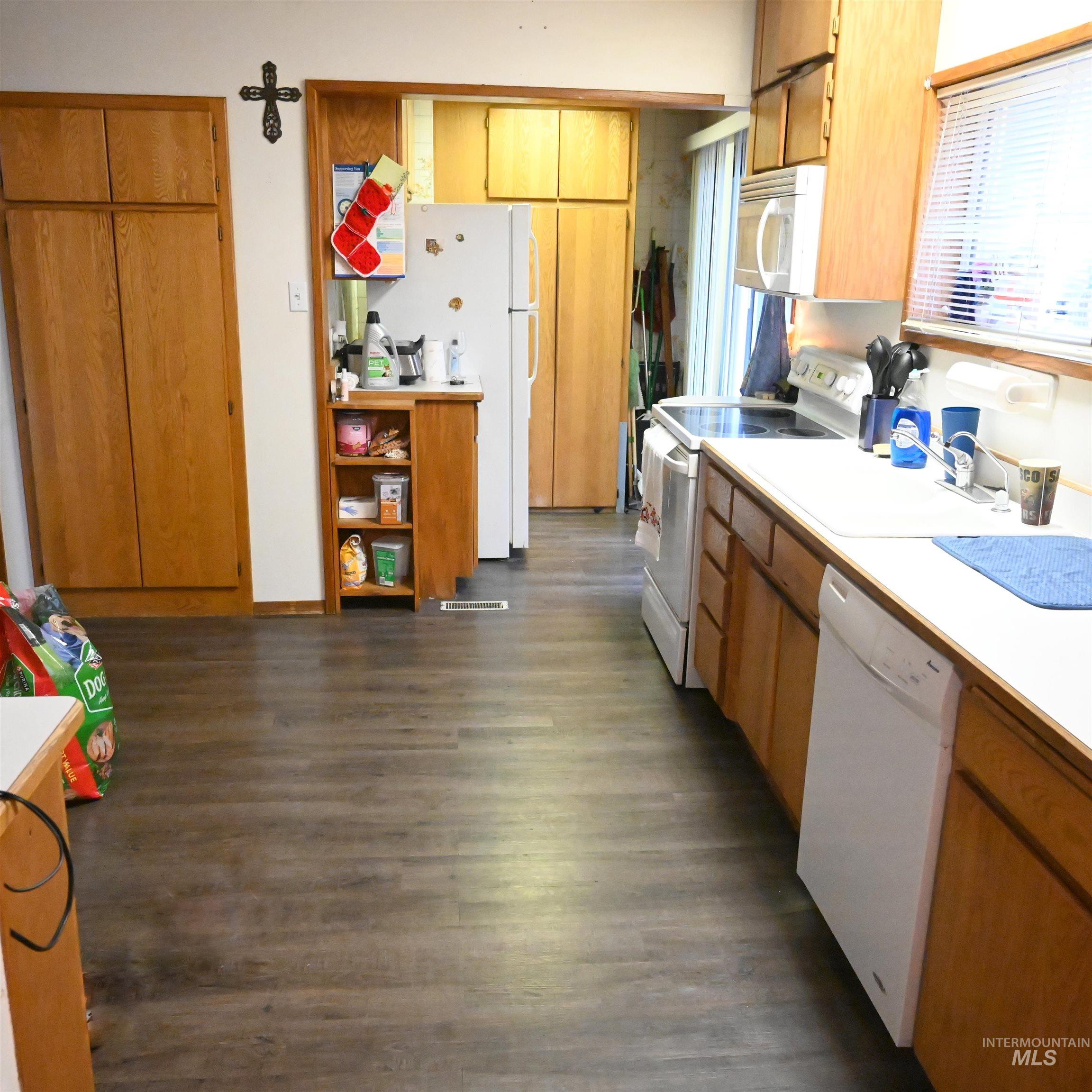 646 Riverside Avenue Orofino, ID 83544 - Photo 4 of 23 Kitchen with white appliances, light countertops, brown cabinets, and dark wood-style floors