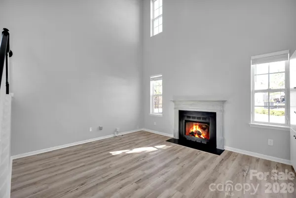 an empty room with wooden floor fireplace and window