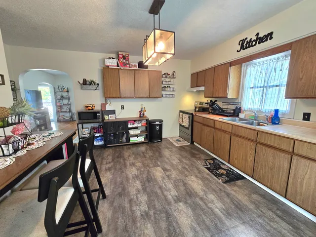 a kitchen with stainless steel appliances a stove a sink dishwasher and a refrigerator with wooden floor