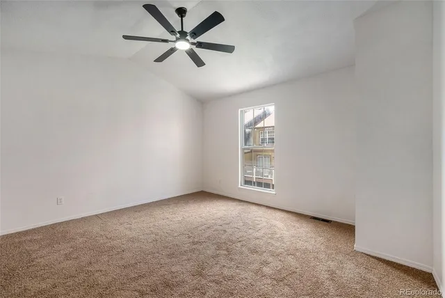 an empty room with windows and fan