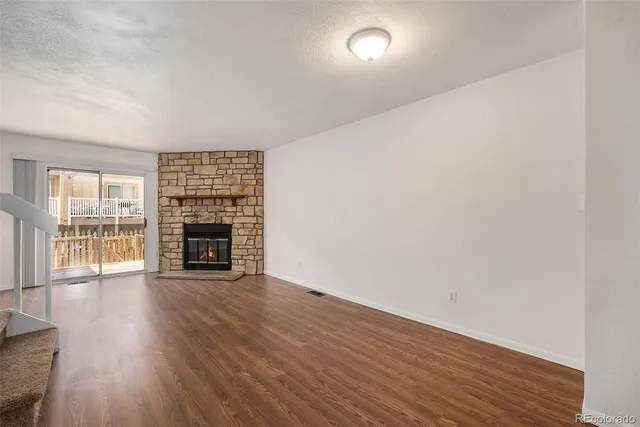 a view of an empty room with wooden floor and a fireplace