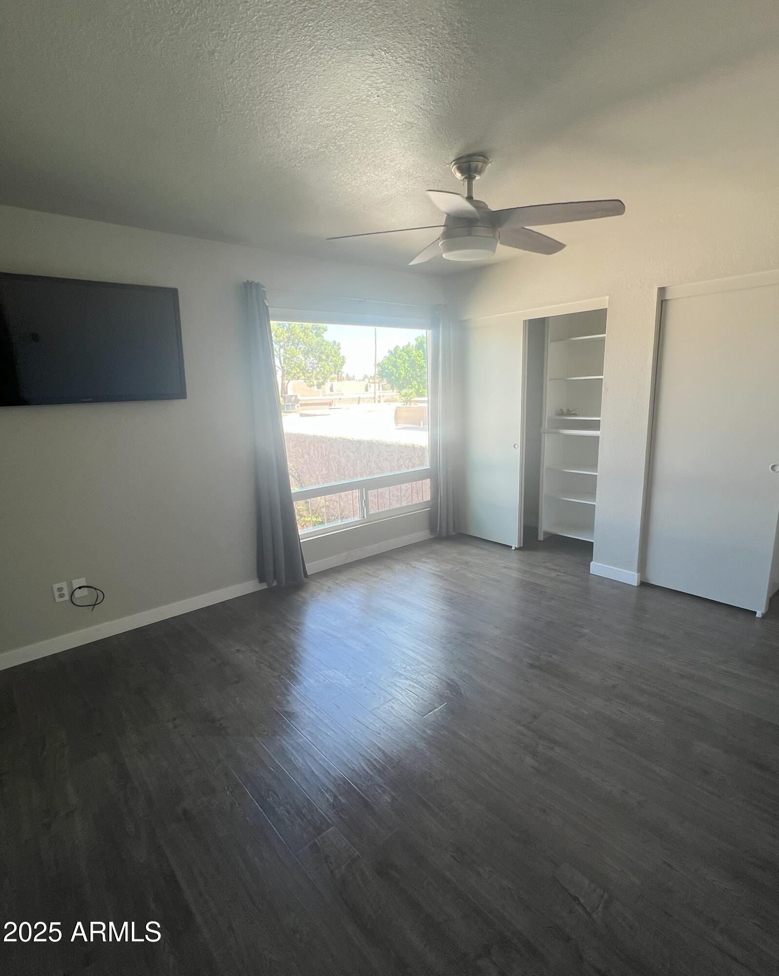 4011 East Charter Oak Road Phoenix, AZ 85032 - Photo 14 of 31 an empty room with wooden floor chandelier fan and windows