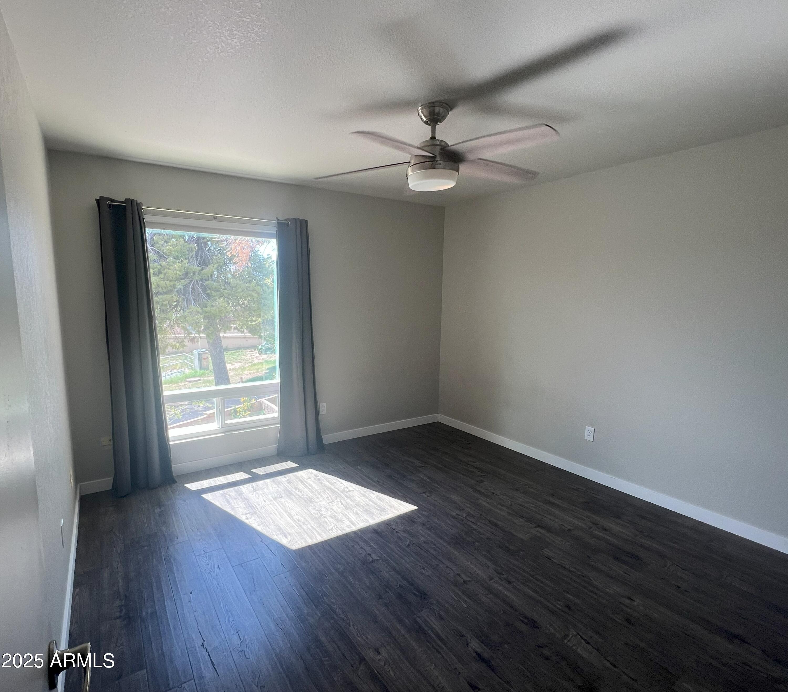 4011 East Charter Oak Road Phoenix, AZ 85032 - Photo 17 of 31 an empty room with wooden floor fan and windows