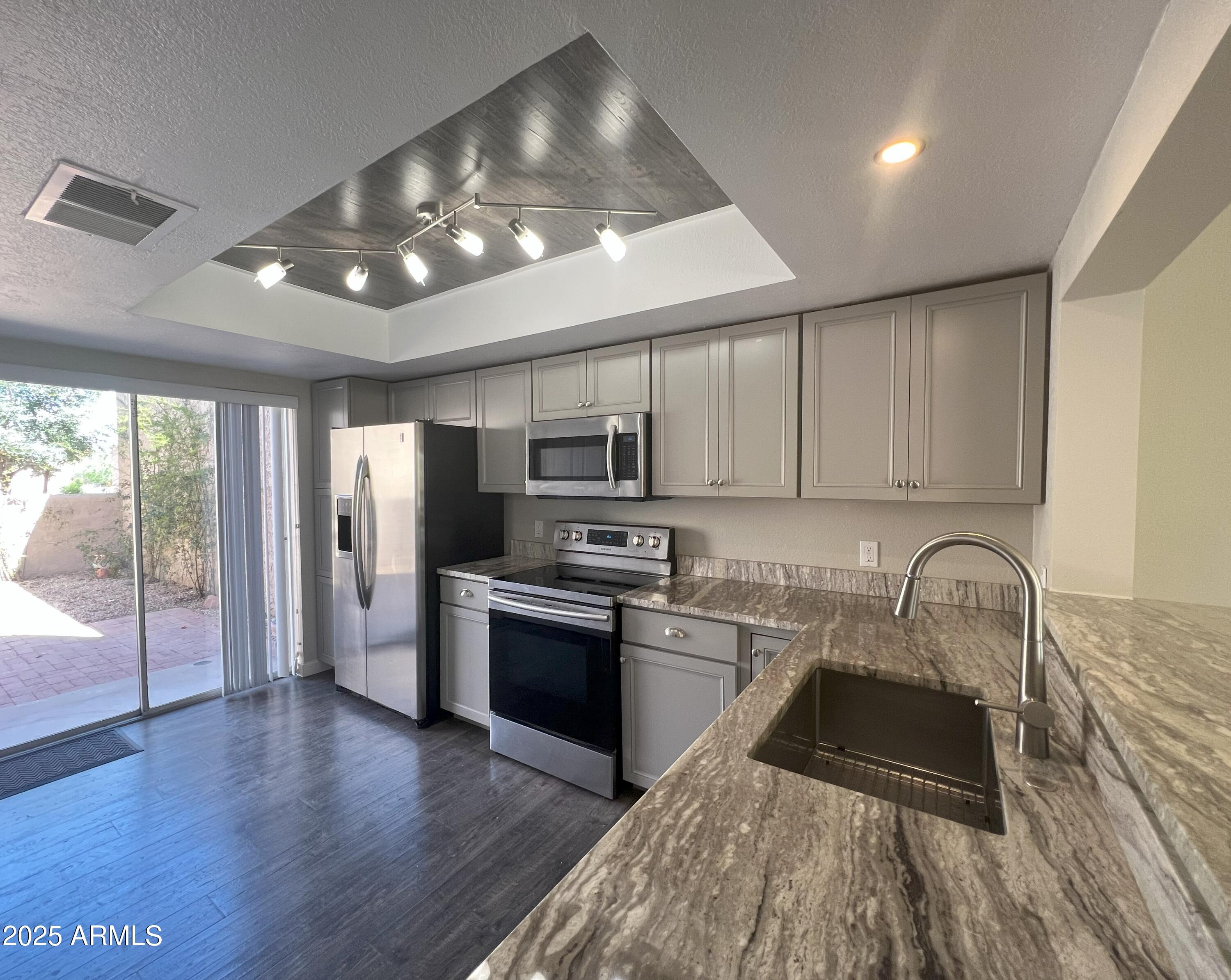 4011 East Charter Oak Road Phoenix, AZ 85032 - Photo 6 of 31 a kitchen with granite countertop stainless steel appliances a sink cabinets and wooden floor