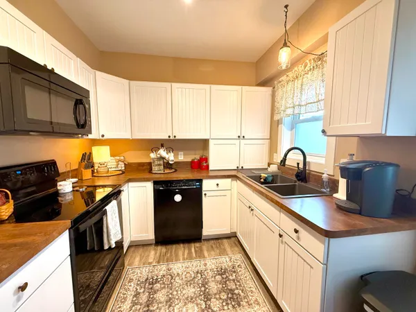 a kitchen with granite countertop a sink a counter space appliances and cabinets