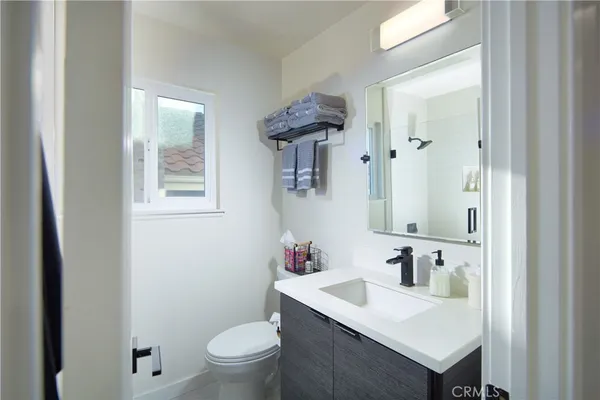 a bathroom with a sink vanity granite toilet and a mirror