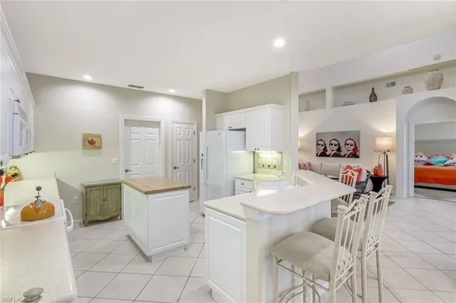 a large white kitchen with a refrigerator a stove a dining table and chairs