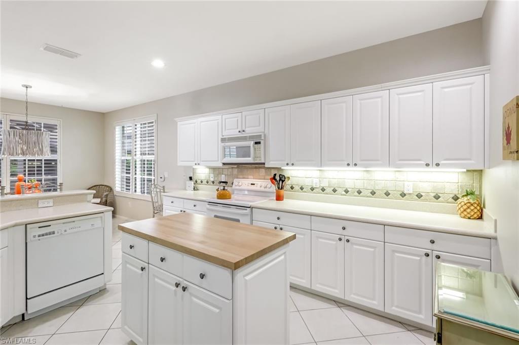 23045 Tree Crest Court Estero, FL 34135 - Photo 12 of 46 Kitchen featuring white cabinetry, butcher block countertops, white appliances, decorative backsplash, and a center island