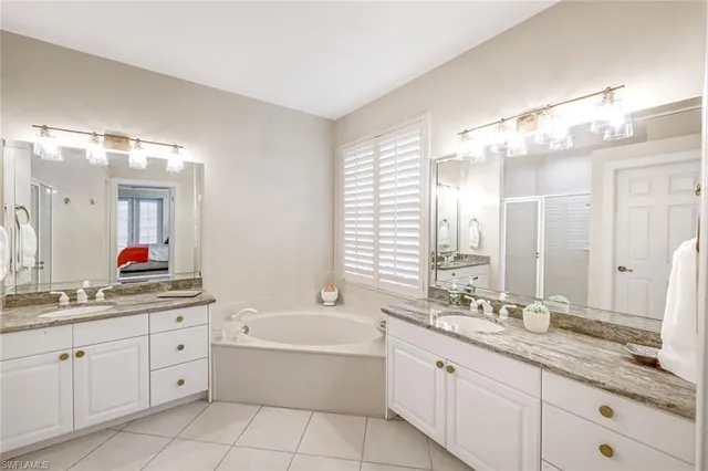 a bathroom with a granite countertop double vanity sink a mirror and a bathtub